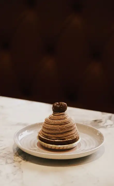 Pâtisserie à la crème de marron sur une assiette blanche, devant un fond sombre